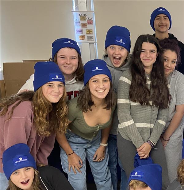  Students smiling in matching blue hats 